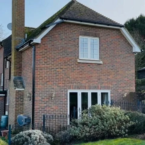 rear of detached property in Wimborne Dorset showing replacement white UPVC fascias, white UPVC soffits and white UPVC bargeboards and new black square UPVC guttering and downpipes