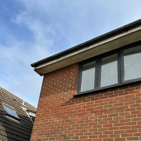 Image showing a detached property in Poole before its timber fascia boards are replaced with new anthracite grey UPVC fascias and soffits and black half round guttering