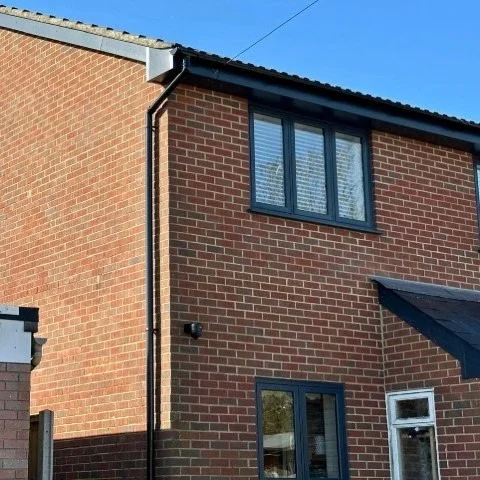 Image showing the front and side of a detached property in Poole with new anthracite grey UPVC fascias and soffits and black half round guttering