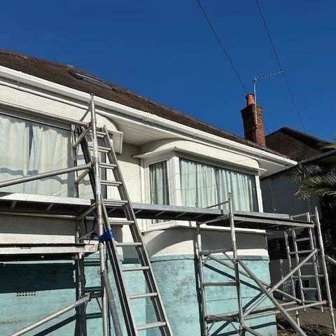 A bungalow with scaffolding set up to fit new fascias and guttering