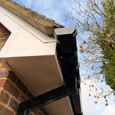 Image shows close up of replacement white UPVC fascias, white UPVC soffits and new black square UPVC guttering and downpipes in Wimborne Dorset