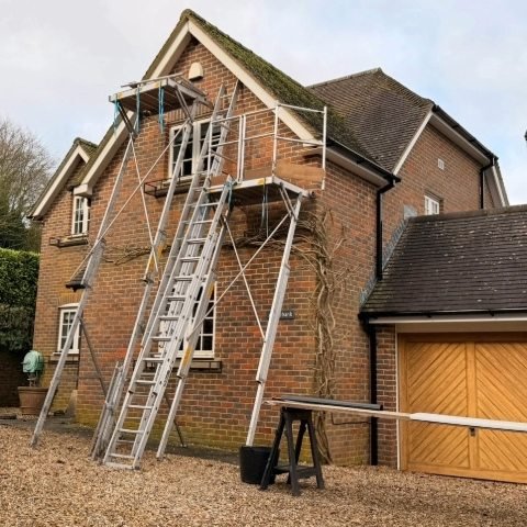 image showing front of detached property in Wimborne Dorset with access equipment to install white UPVC fascias, white UPVC soffits and white UPVC bargeboards and new black square UPVC guttering and downpipes