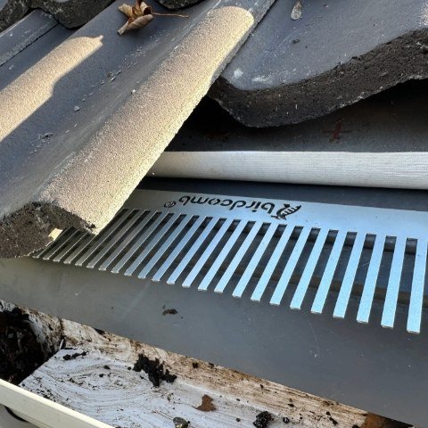 Image shows close up of metal birdcomb bird guard system being installed under tiles in Christchurch, Dorset