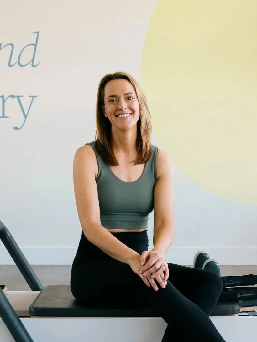 Oner of Salt Pilates Studio in Balaclava, Alicia sitting on Pilates Reformer in the Salt Studio.