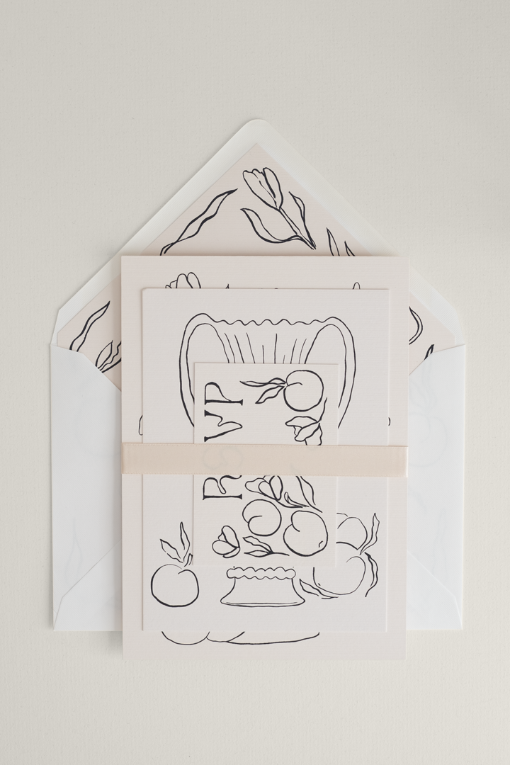Tulips wedding invitation suite stacked together, finished with a sleek pearl satin ribbon band, and placed on top of an art-led patterned envelope liner.