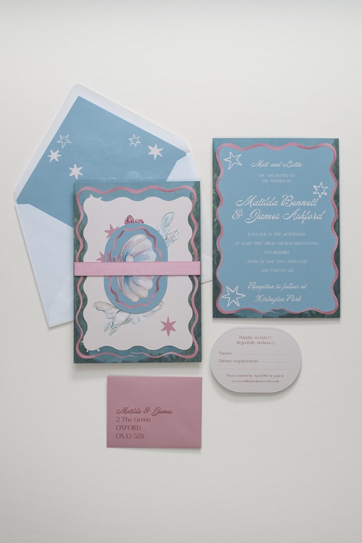 The Coquette wedding invitation suite bound by a rose pink double-faced satin ribbon band, displayed beside the flat-laid RSVP and invitation reverse details and envelope.
