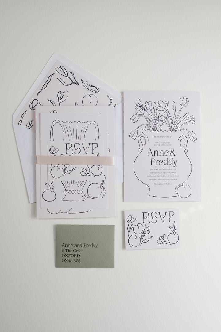 The Tulips wedding invitation suite bound by an pearl satin ribbon band, displayed beside the flat-laid RSVP and invitation reverse details and envelope.