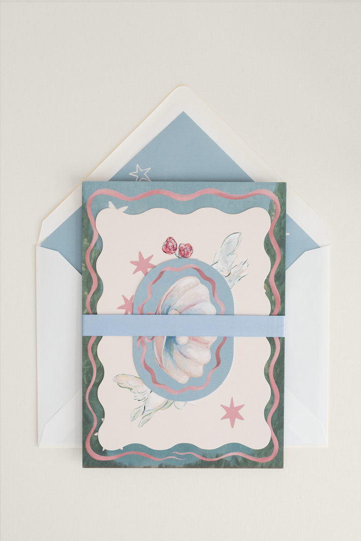 Coquette wedding invitation suite carefully stacked and finished with a cornflower satin ribbon band, placed on a whimsical lined invitation envelope.
