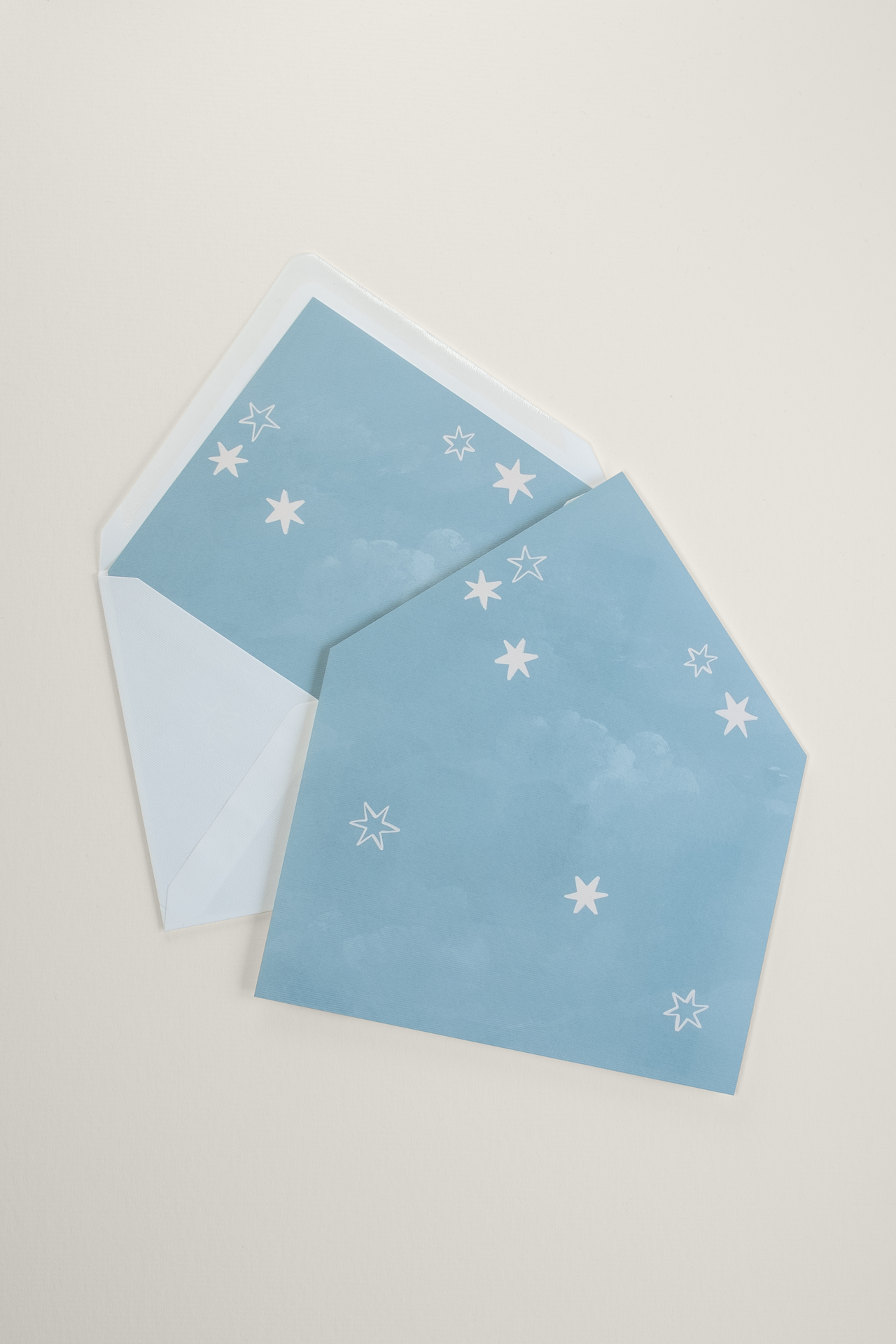 Coquette wedding invitation envelope liner featuring an all-over hand-drawn star pattern, styled over an open envelope showing the inner cloud motif.