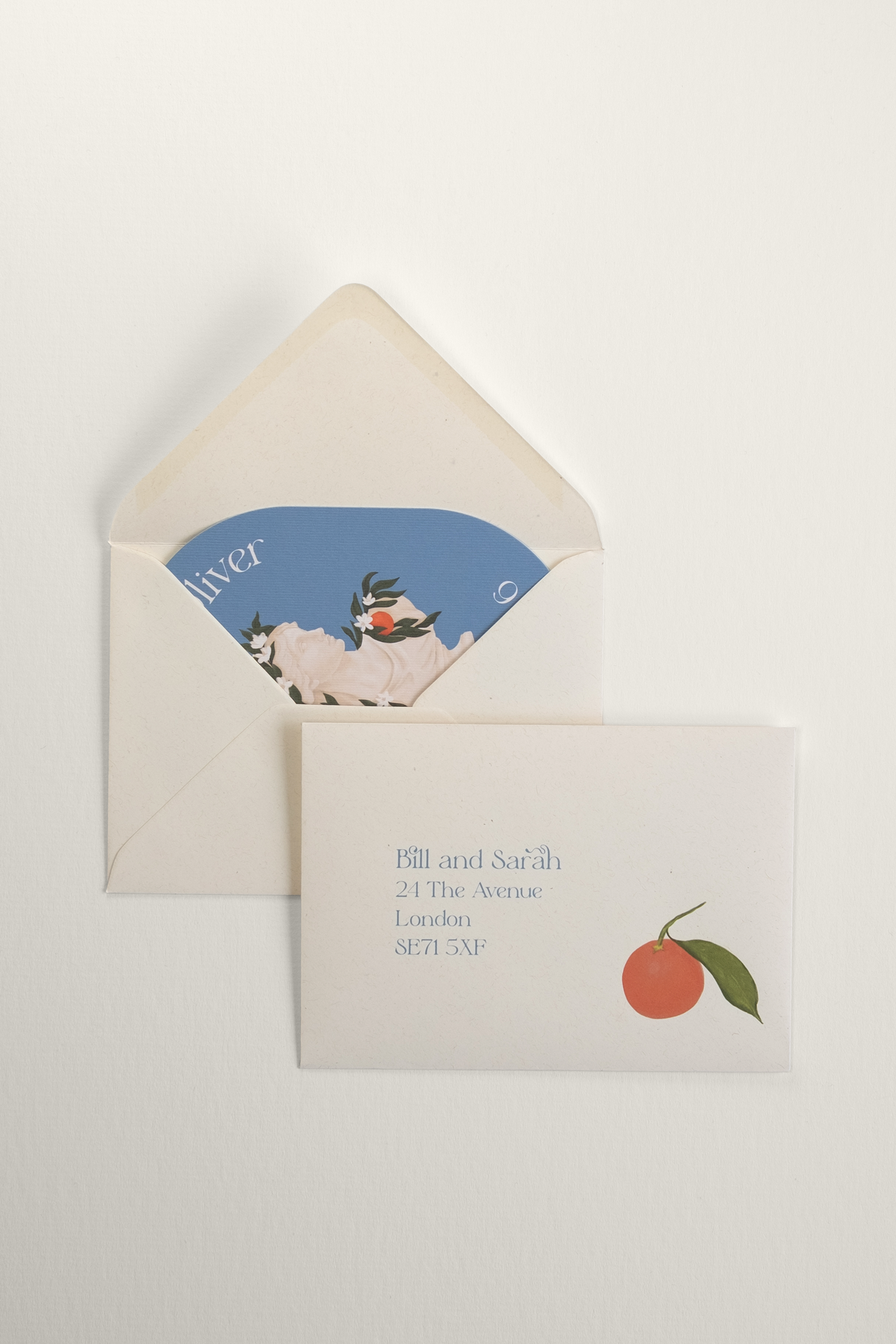 An addressed recycled flecked cream wedding envelope, with an Orangery collection Save the Date card tucked neatly inside to reveal the classical bust illustration.