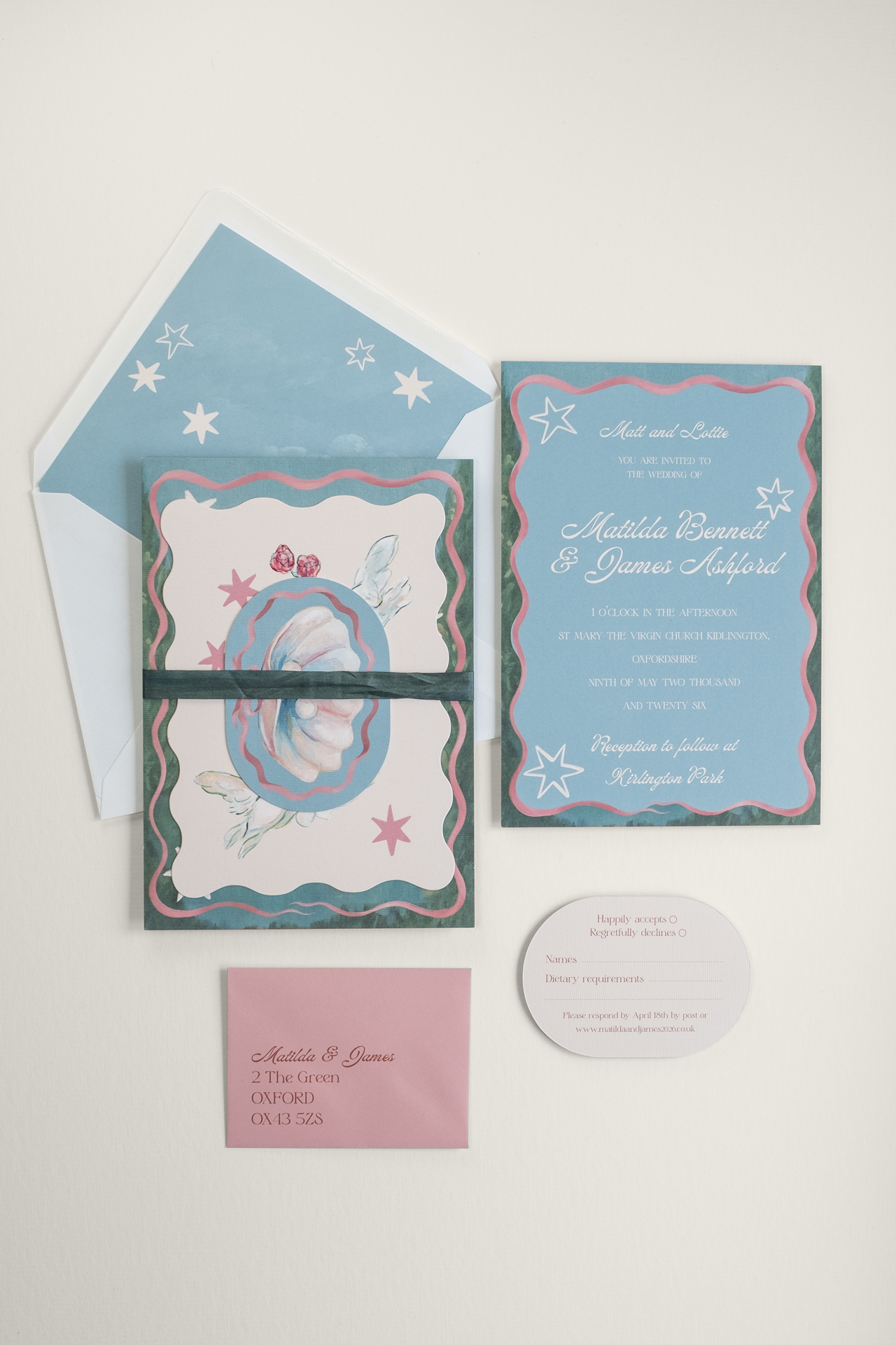 The Coquette wedding invitation suite bound by a dark green closed-edge Habotai silk ribbon, displayed beside the flat-laid RSVP and invitation reverse details and envelope.