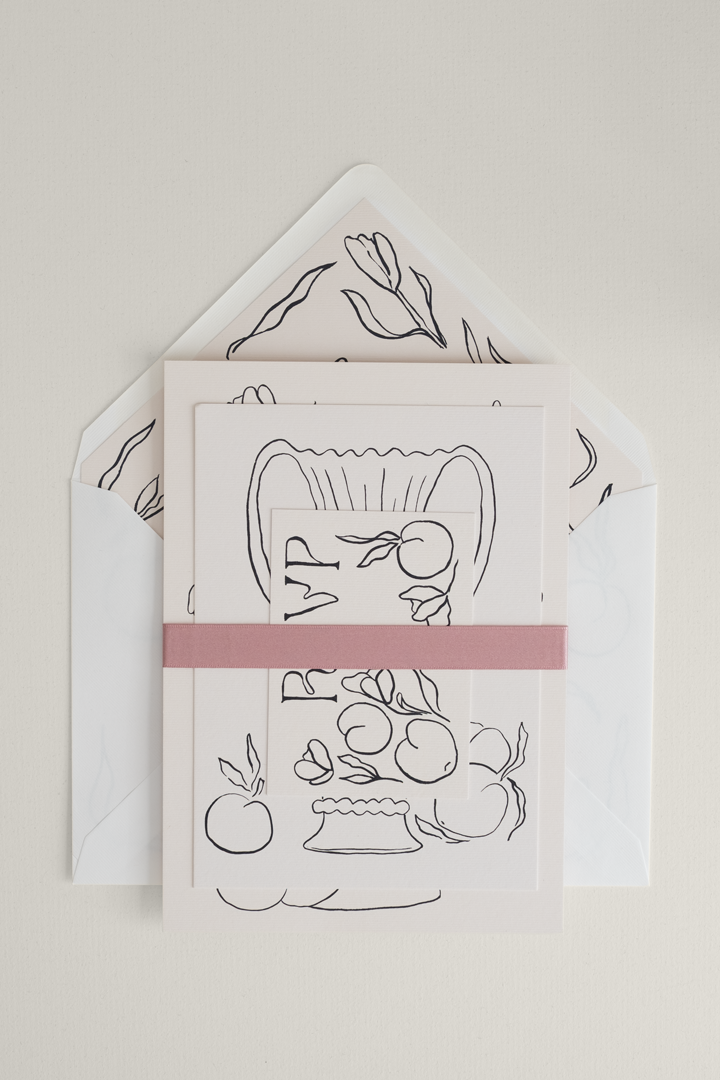 Monochromatic Tulips wedding invitation suite stacked and finished with a rose satin ribbon band, set against a whimsical open envelope with a custom liner.
