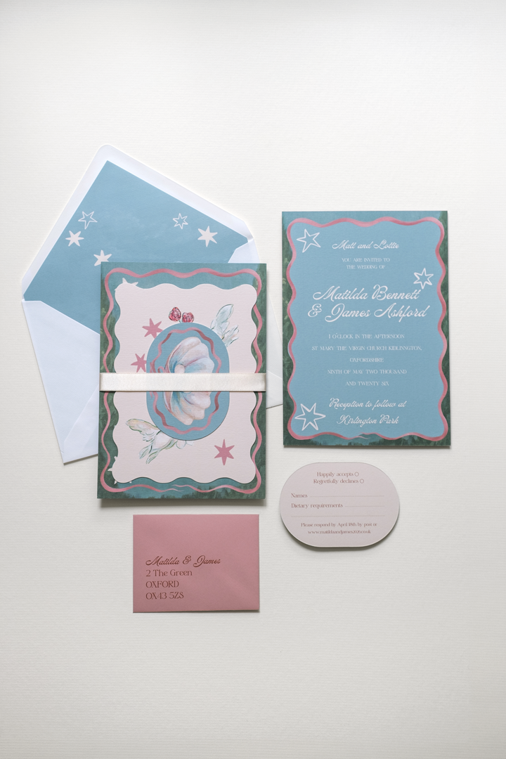 The Coquette wedding invitation suite bound by a pearl double-faced satin ribbon band, displayed beside the flat-laid RSVP and invitation reverse details and envelope.