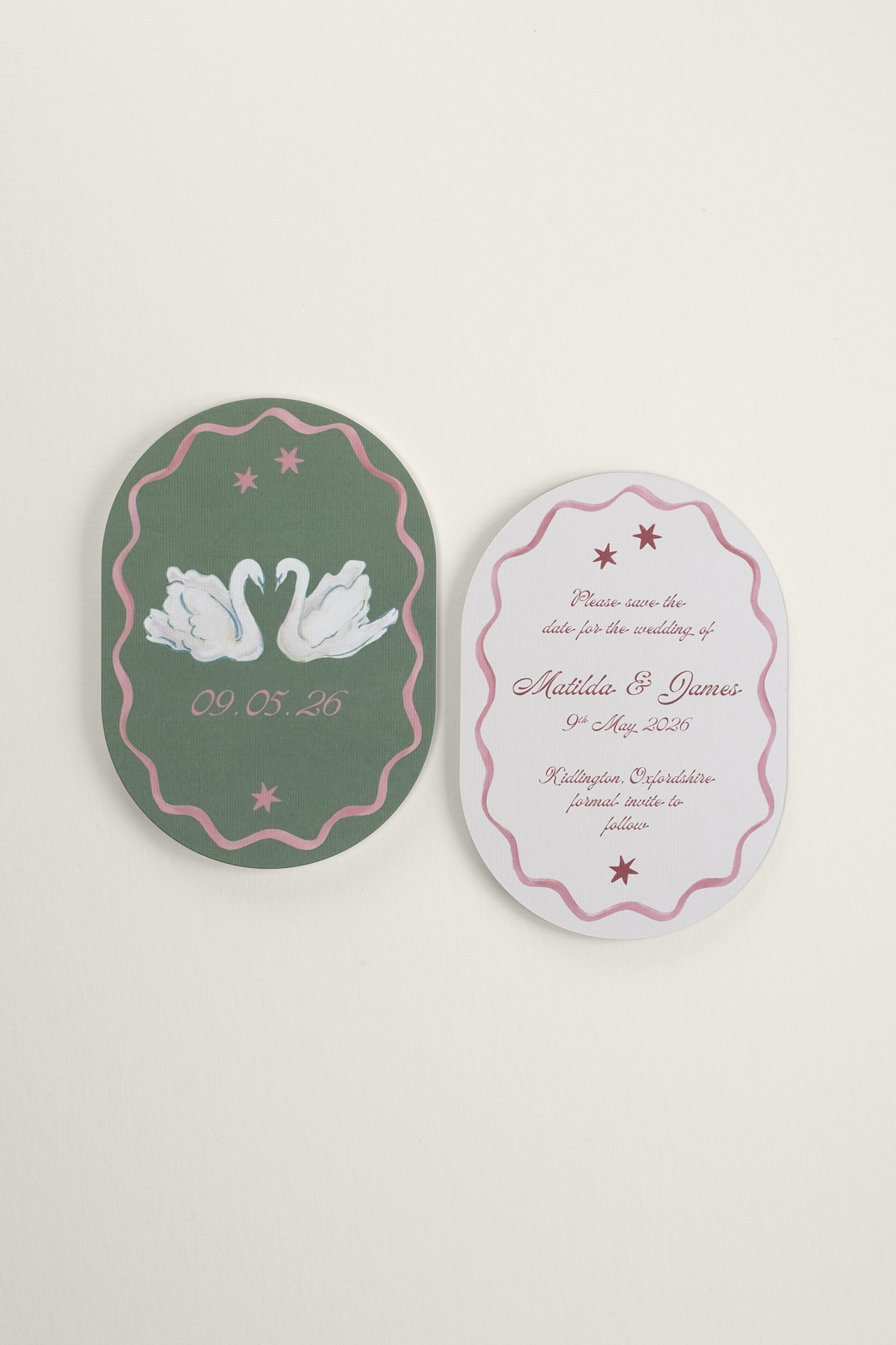 Flat lay of the double-arched Coquette wedding Save the Date card, showcasing a romantic gouache swan centerpiece with a wavy ribbon border alongside the typeset reverse side.