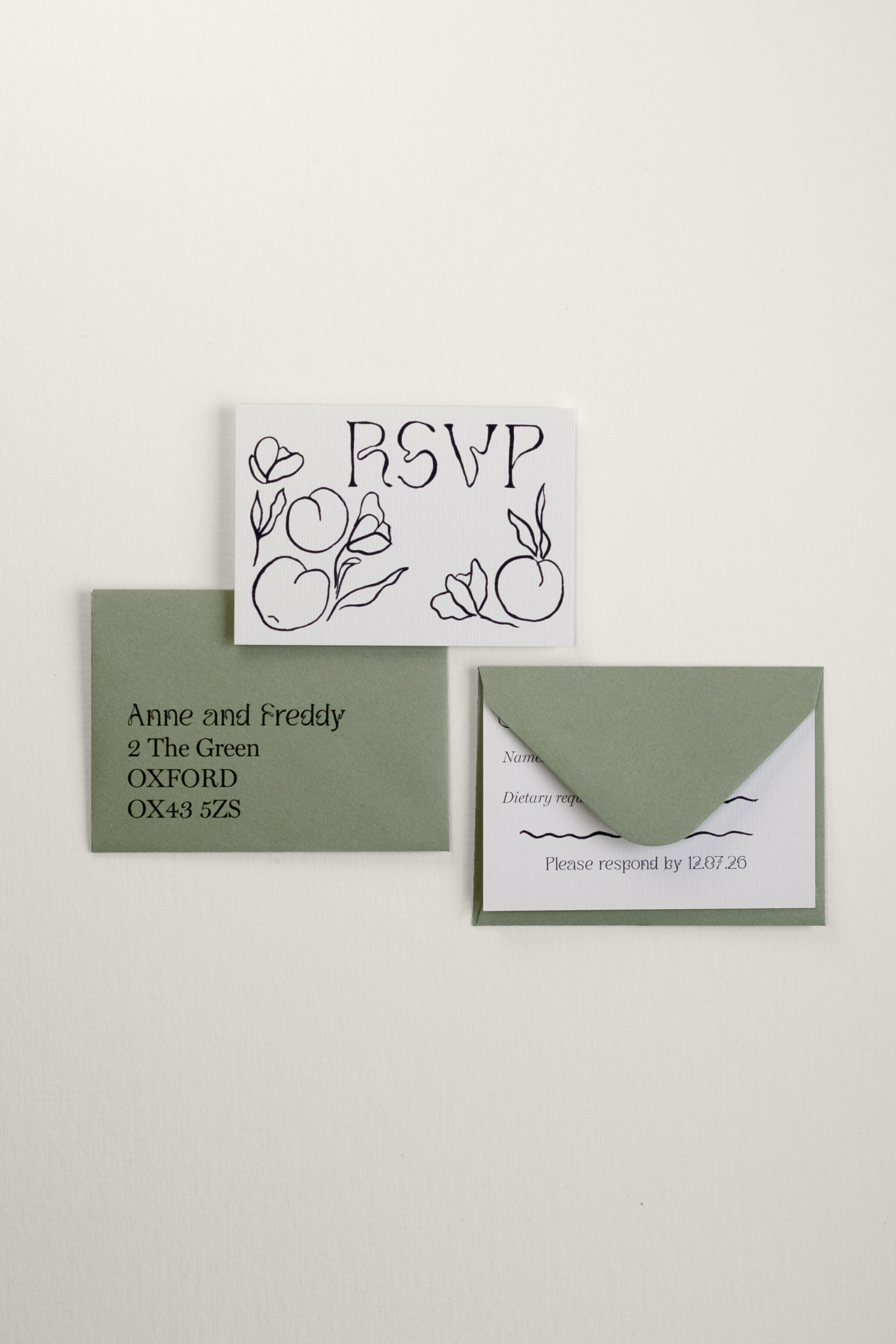 Tulips wedding RSVP card front laid next to an addressed envelope, with the reverse response side tucked neatly inside a matching pale sage green envelope flap.