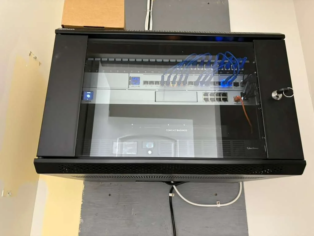 Top view of a network switch and fiber optic equipment inside a black security enclosure with a glass top.