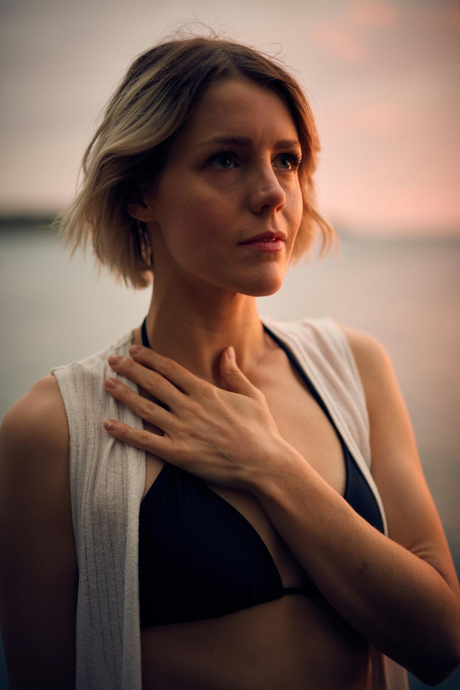 Une femme regarde pensivement un coucher du soleil. Attend-elle un message du ciel?