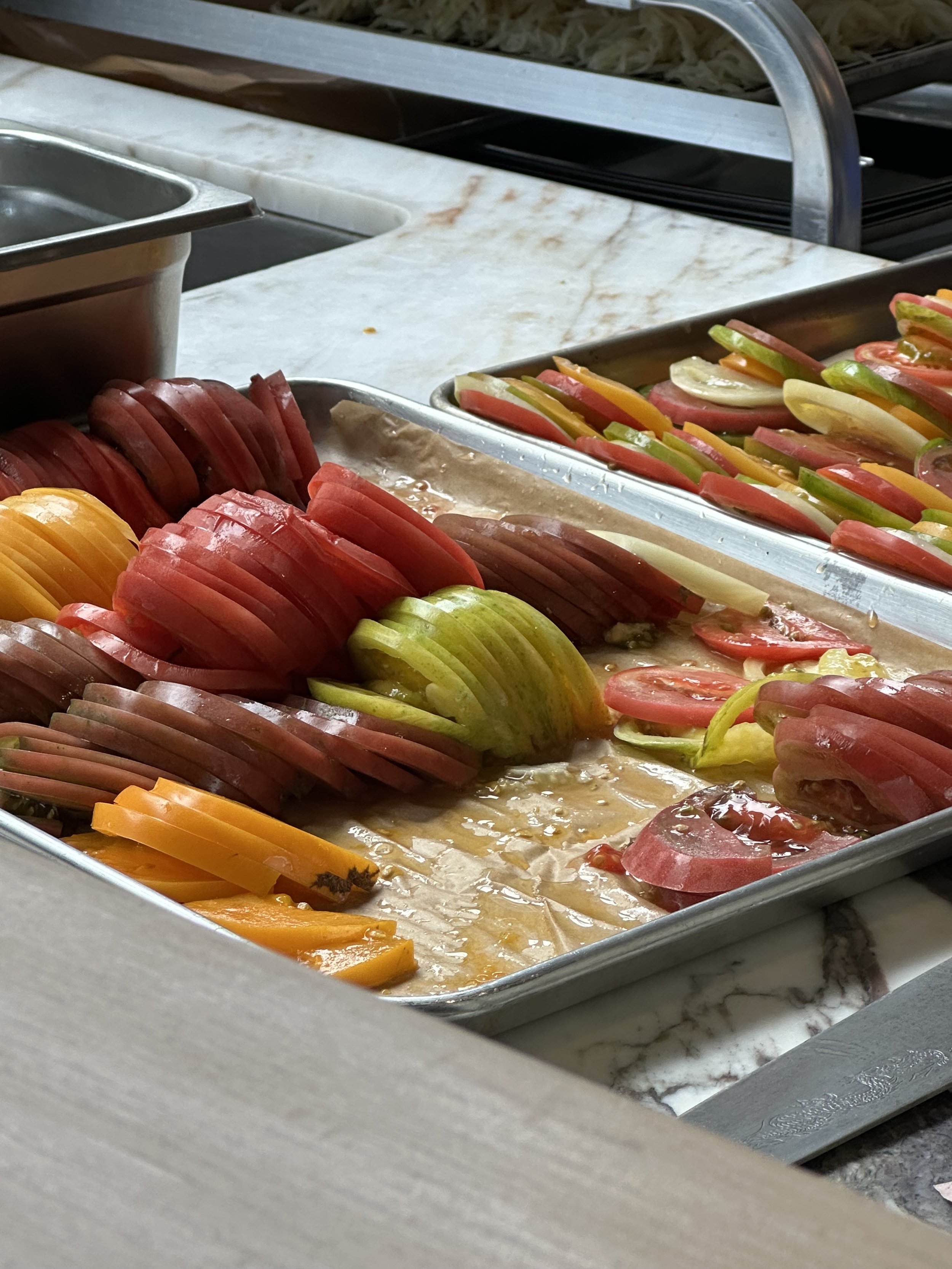 Tray of sliced tomatoes, green bell peppers, and yellow and red bell peppers.