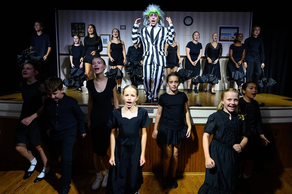Children and a performer dressed as Beetlejuice on stage during a theatrical performance.