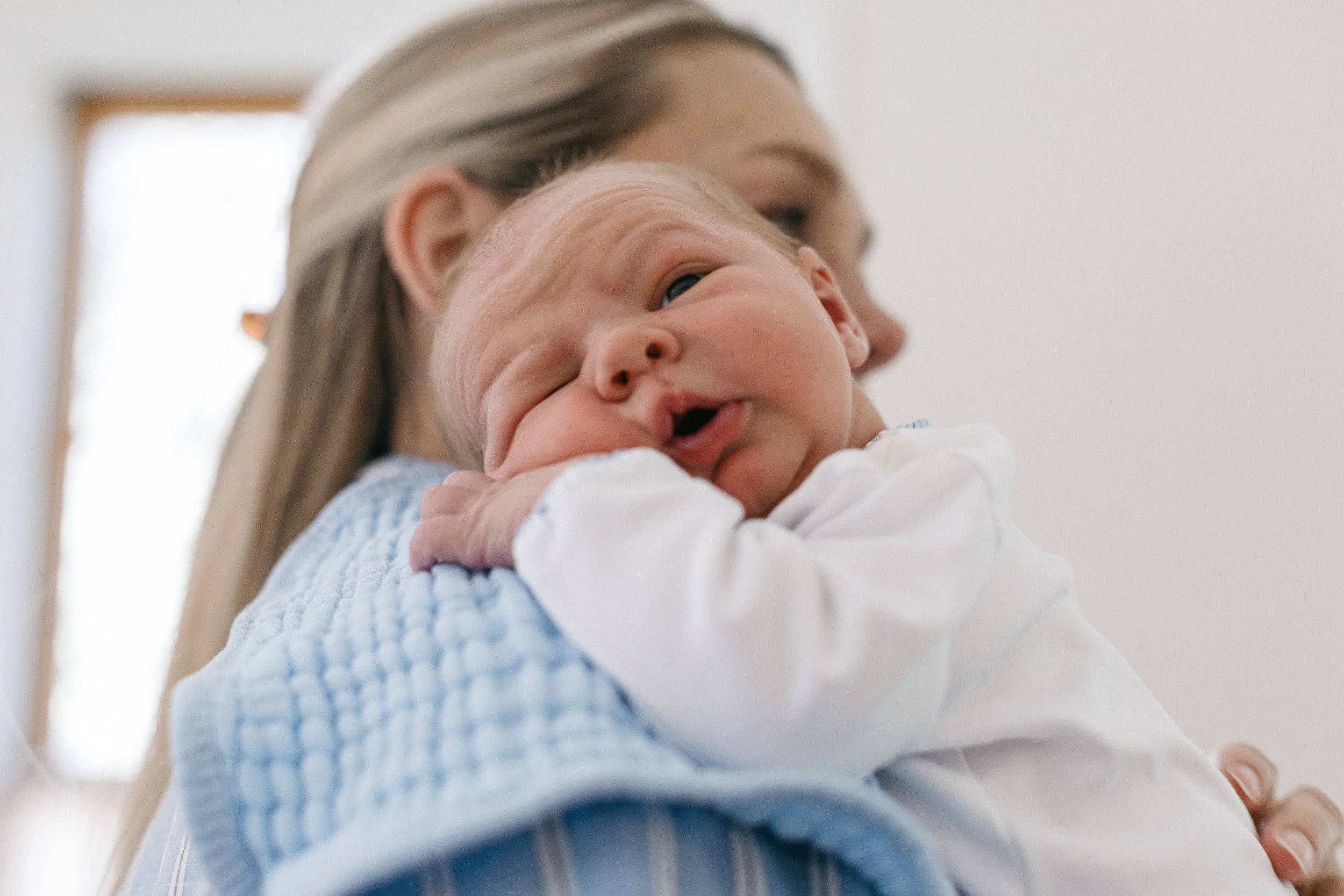 A woman holding a baby close to her face indoors with a white background.