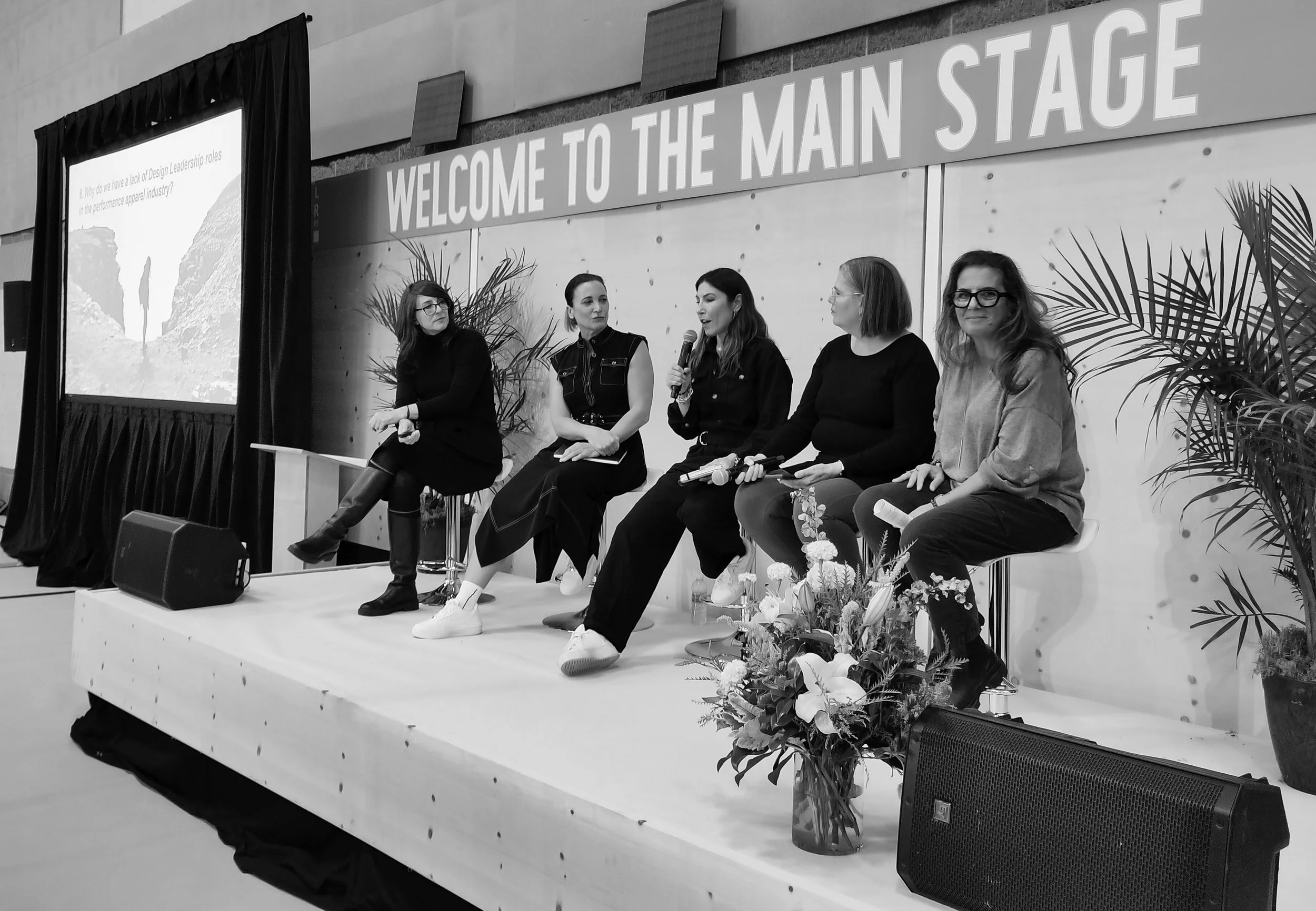 Black and white photograph of Michelle Rose participating in an industry expert panel on the main stage, discussing design leadership roles.