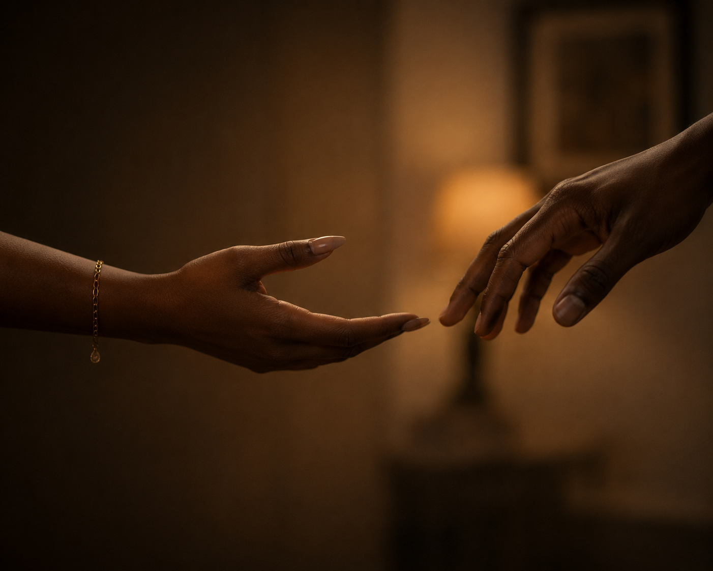 An open black female hand reaching across a soft-lit space toward another hand that is a black male hand that is clean, not yet touching. Hope without resolution.