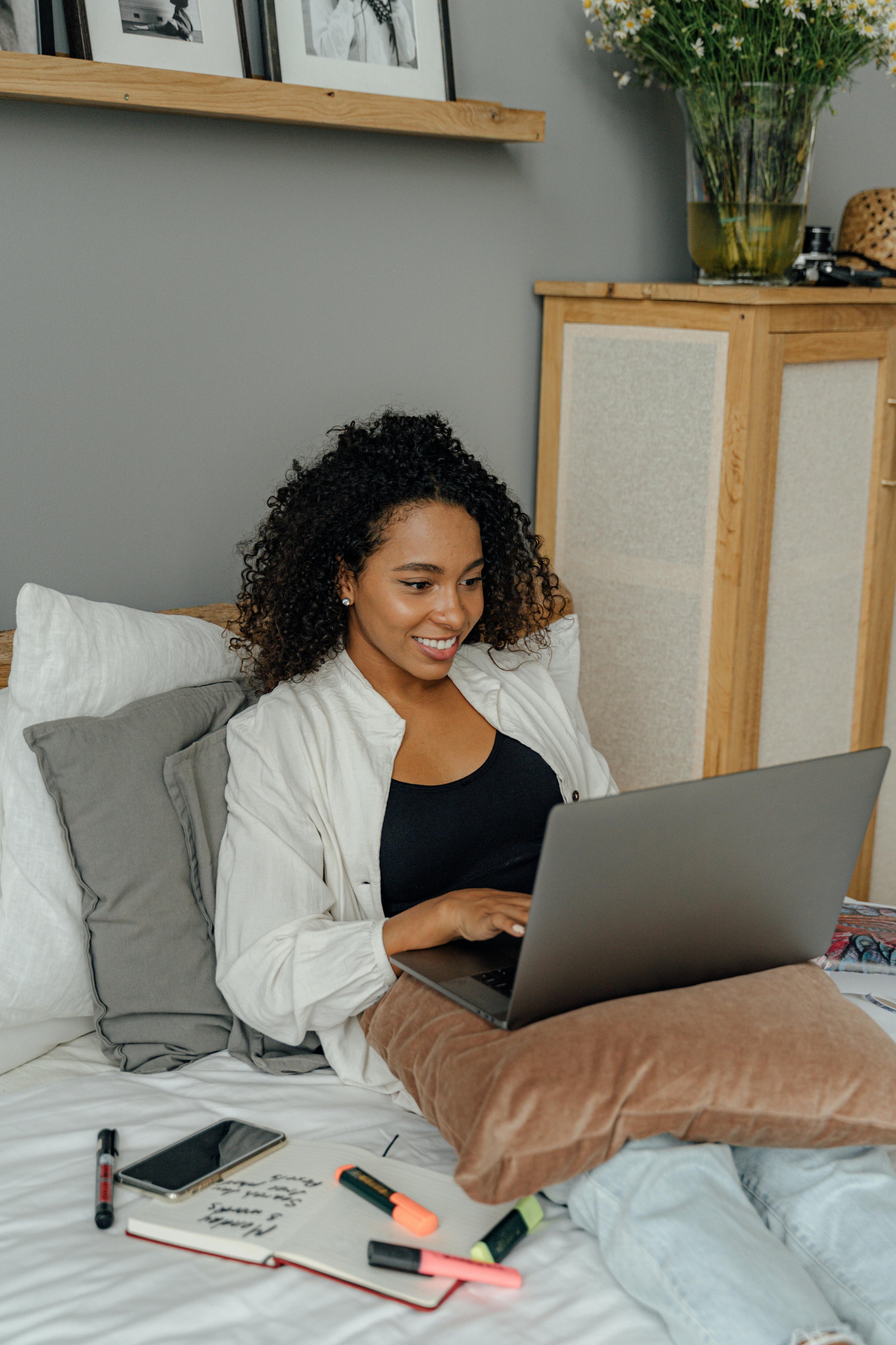 An African American woman with a beige headwrap with a headset sits comfortably, engaging with a tablet. This highlights the flexibility and accessibility of online counseling through video and phone sessions.