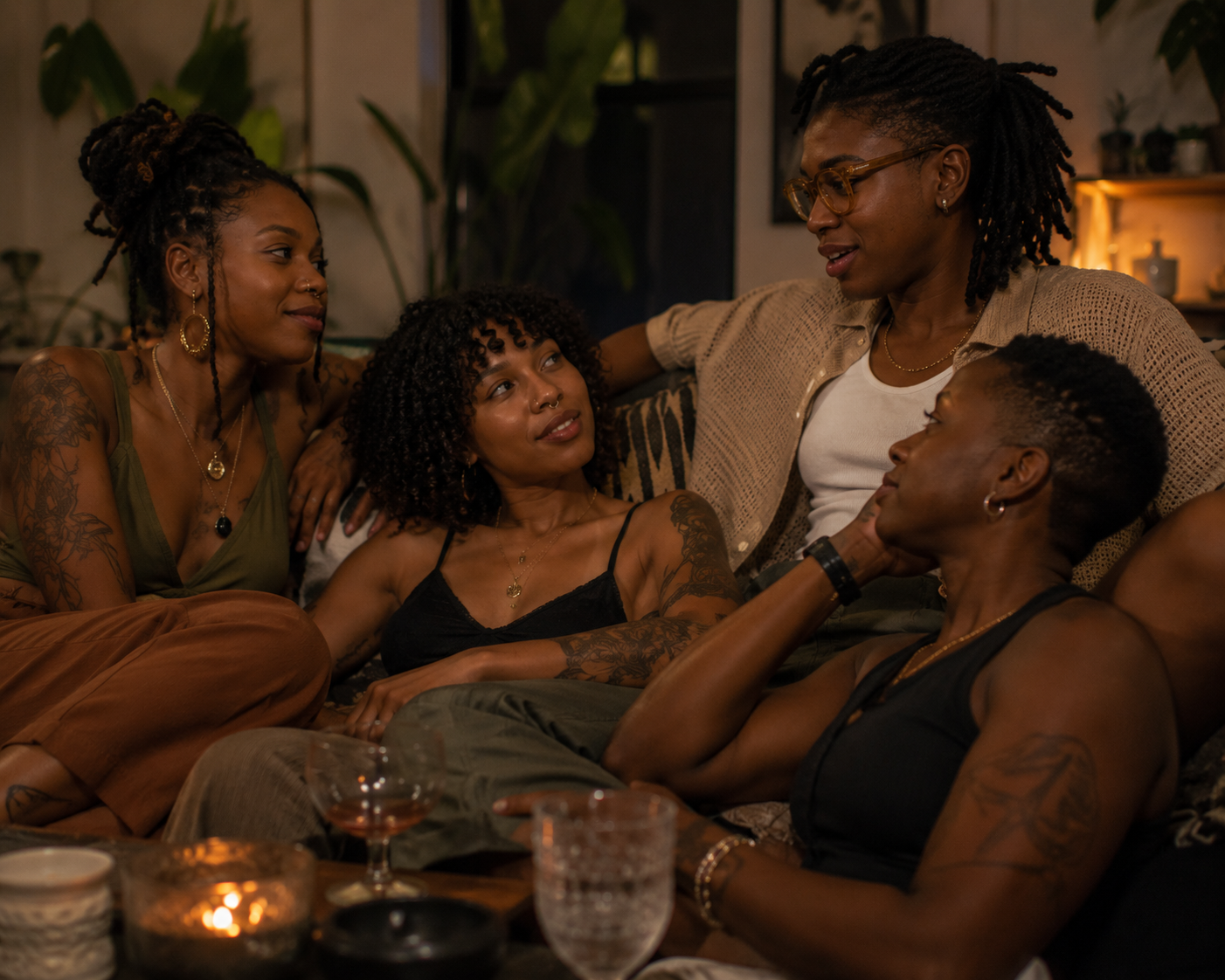 Four Black women engaged in a warm and connected conversation, illustrating emotional intimacy, communication, and relationship connection within an ENM relationship structure.