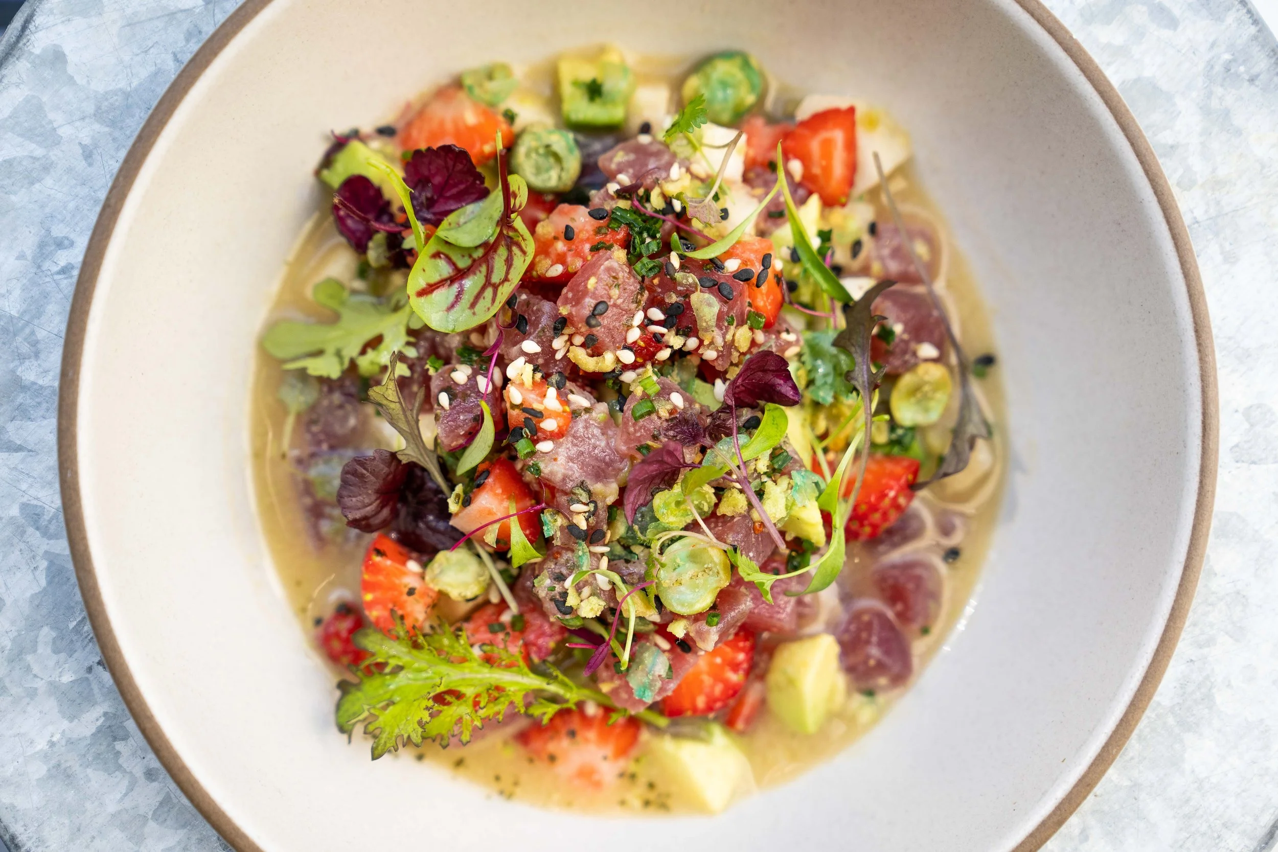 Tuna tartare with strawberries, avocado, apple, sesame seeds, and micro greens on top.