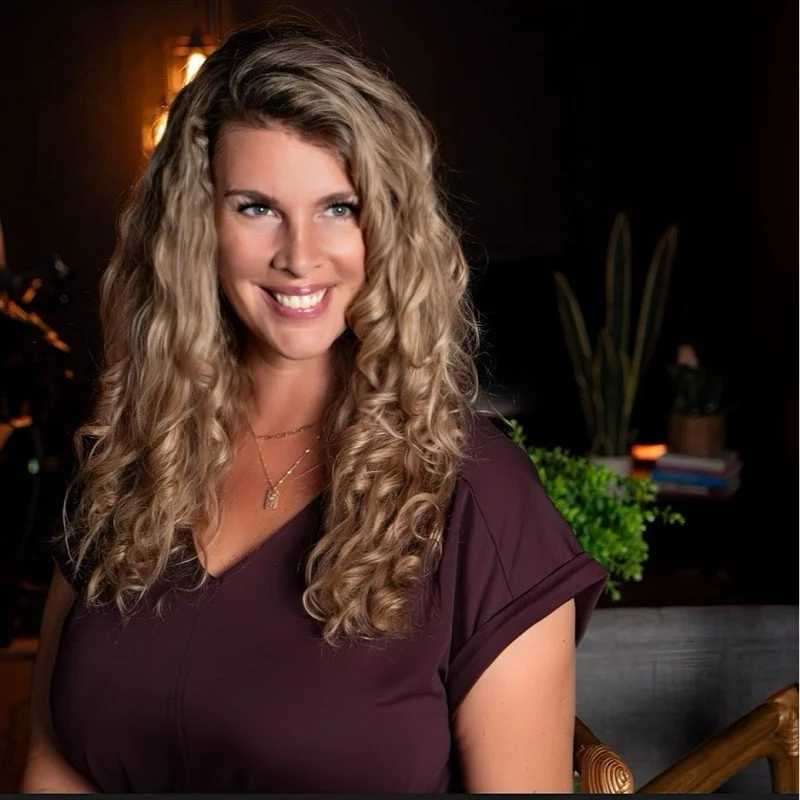 Smiling person with glasses and an afro hairstyle in a casual setting.