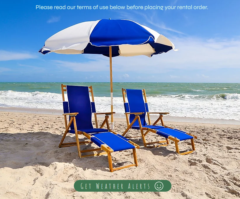 Two blue lounge chairs and a blue and white umbrella on a sandy beach with ocean waves in the background.