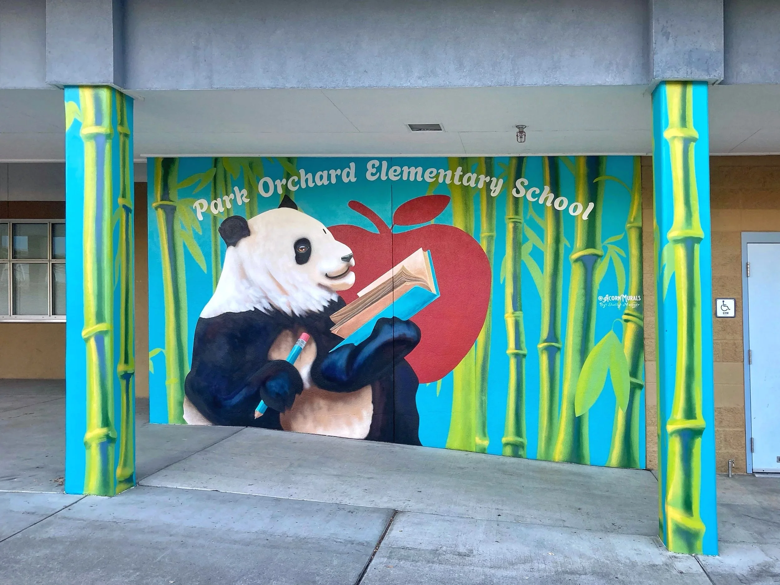 Acorn Murals Shelly Metzger Hungry for Knowledge Panda mural for Park Orchard Elementary School Kent, WA Panda holding a book and pencil over an apple symbol, surrounded by a bamboo forest and cheery blue background. Welcomes students and families du