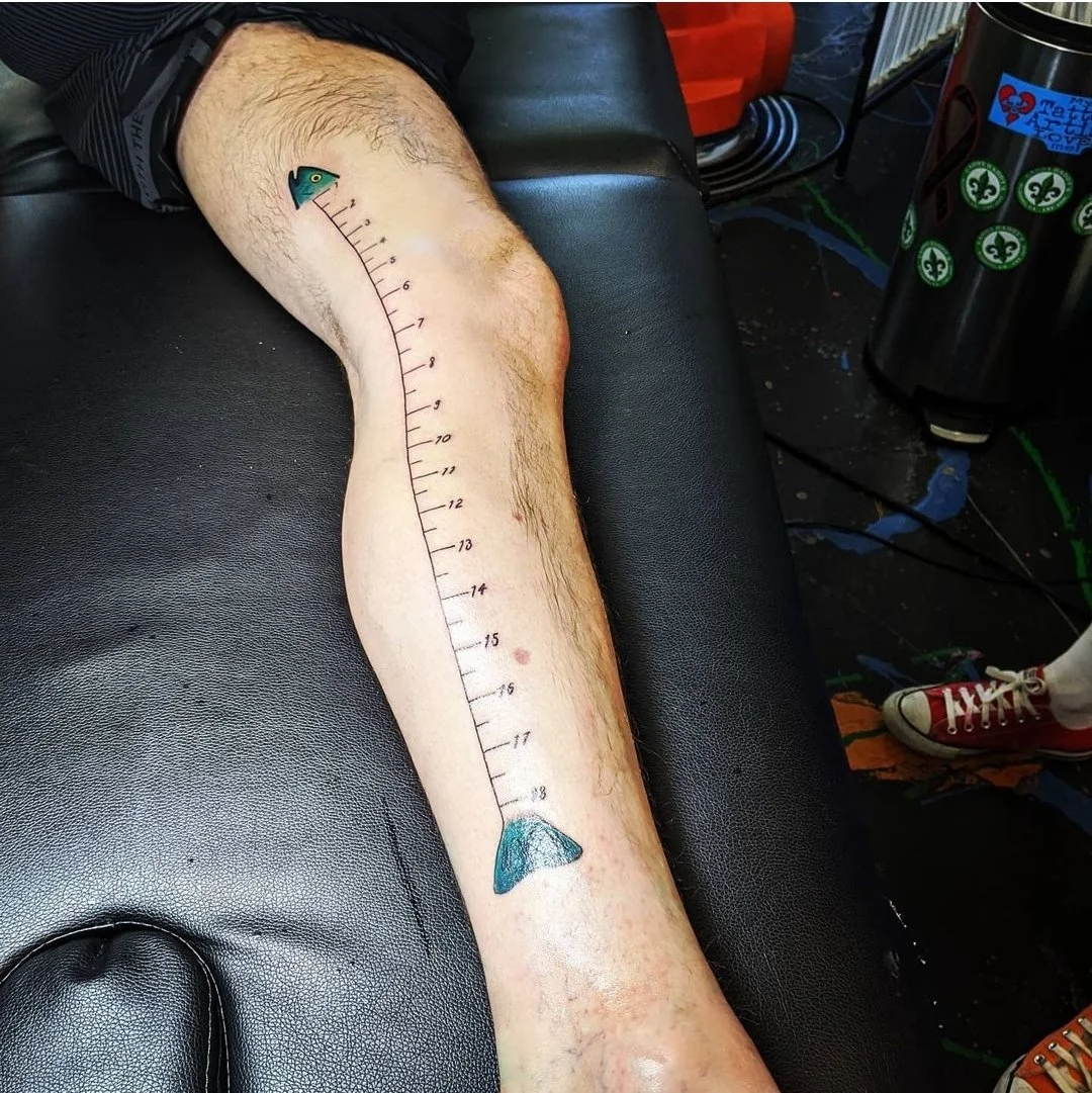 Fish ruler tattoo on a man's leg