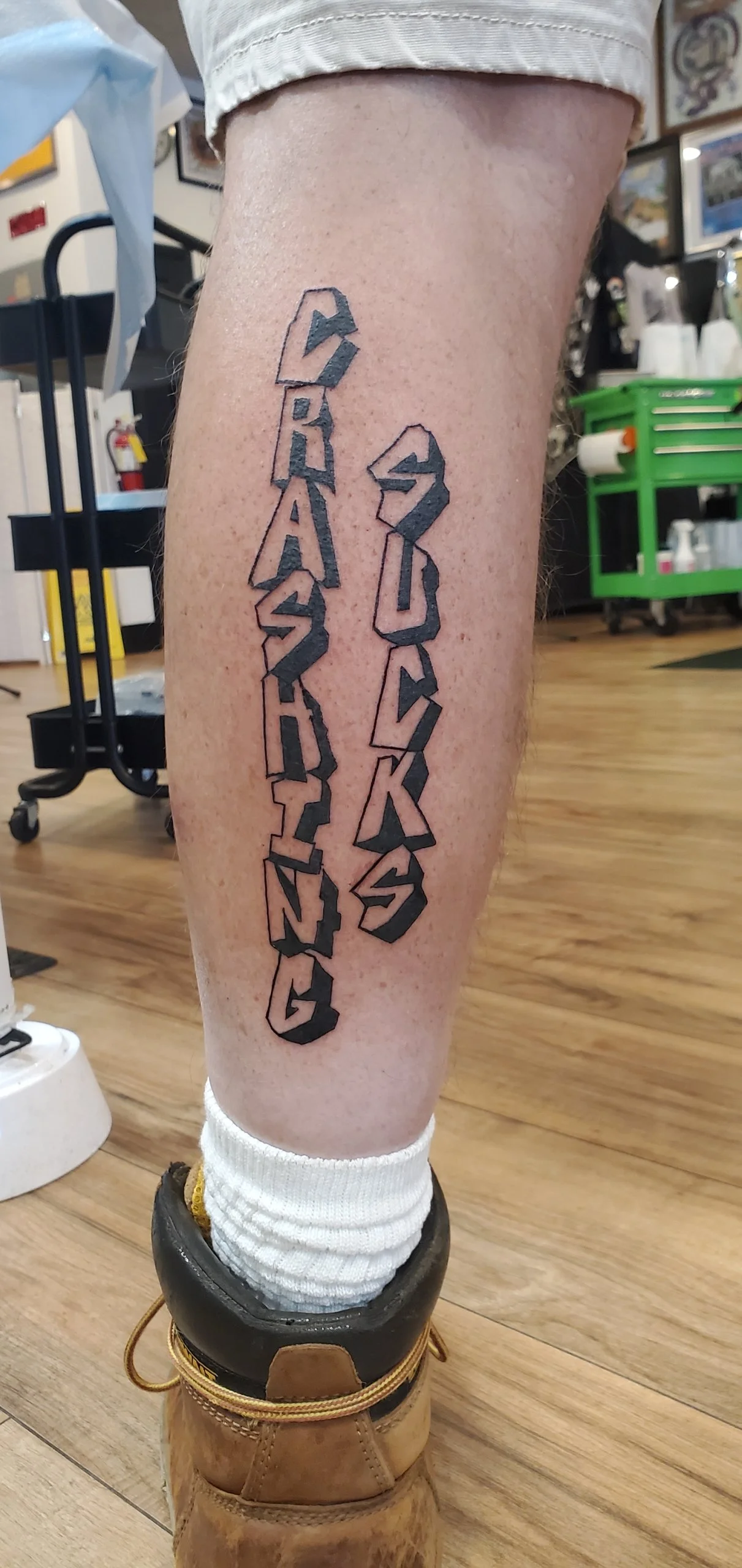 Tattoo on person's leg reading 'DREAMS' on the left and 'SOMETHING' on the right in stylized 3D block letters.