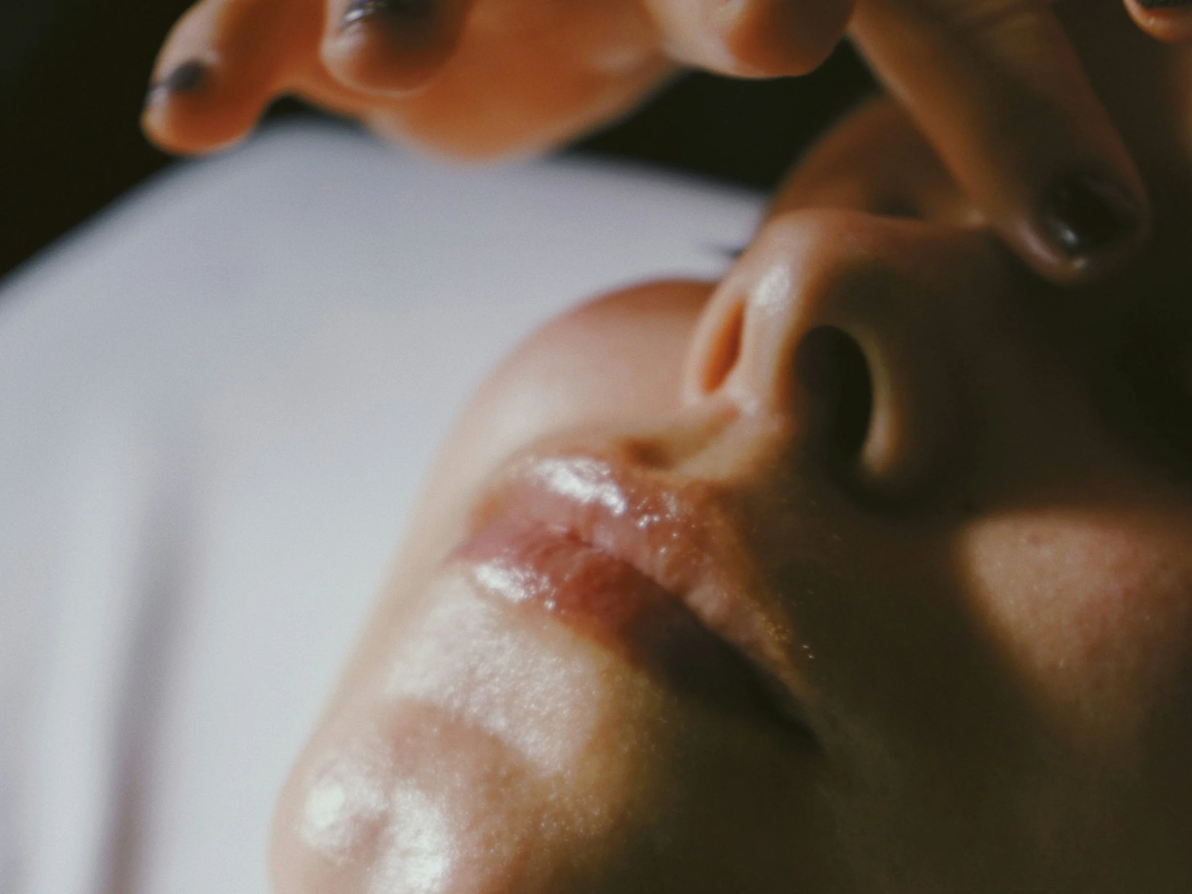 Close-up of a person's face with eyes closed, lying down, and a hand gently touching their forehead receiving a facial treatment at lemurian skin + soul in Toronto and Etobicoke