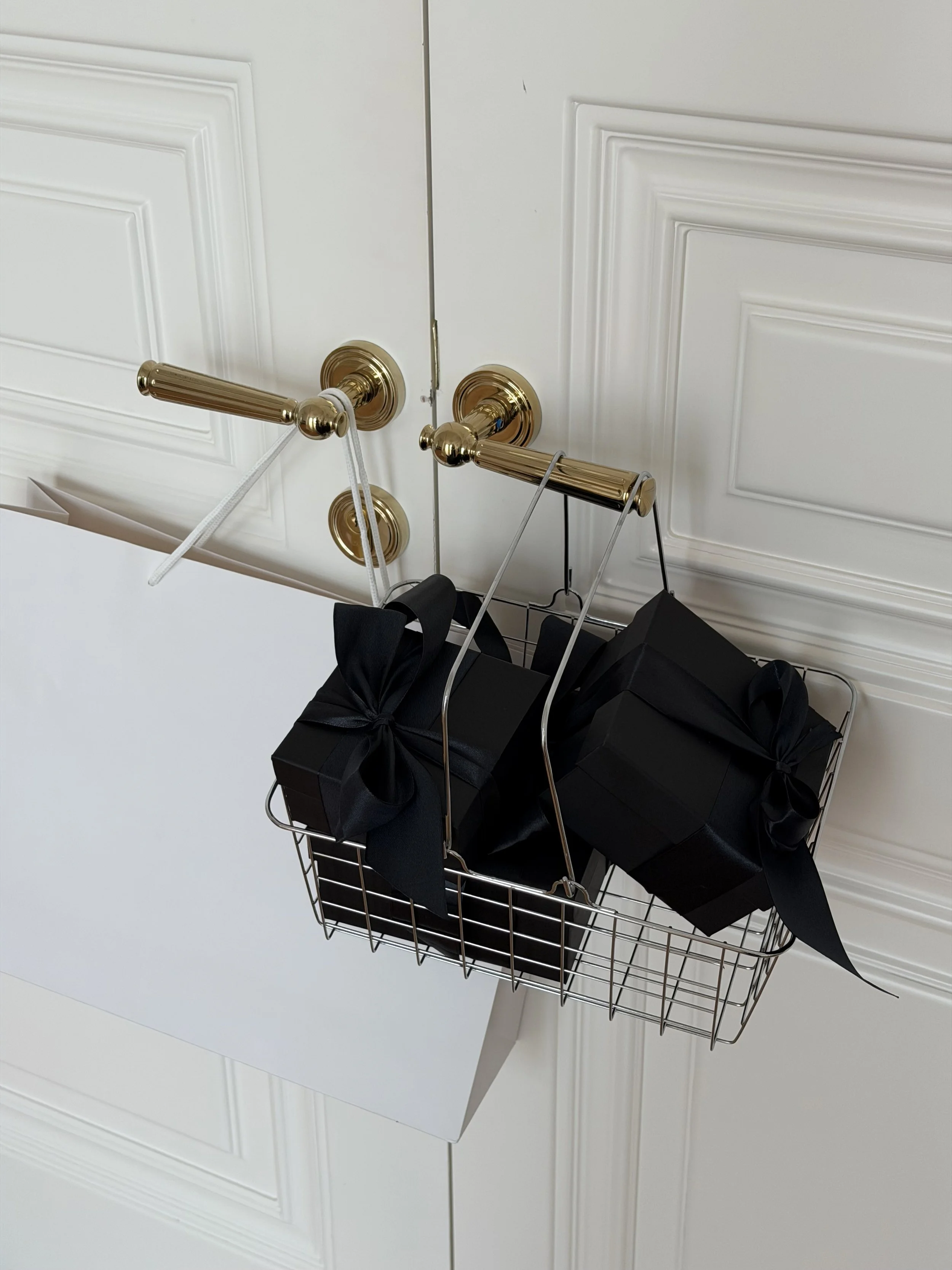Wire basket filled with black gifts hanging on gold door handles, Black Friday image