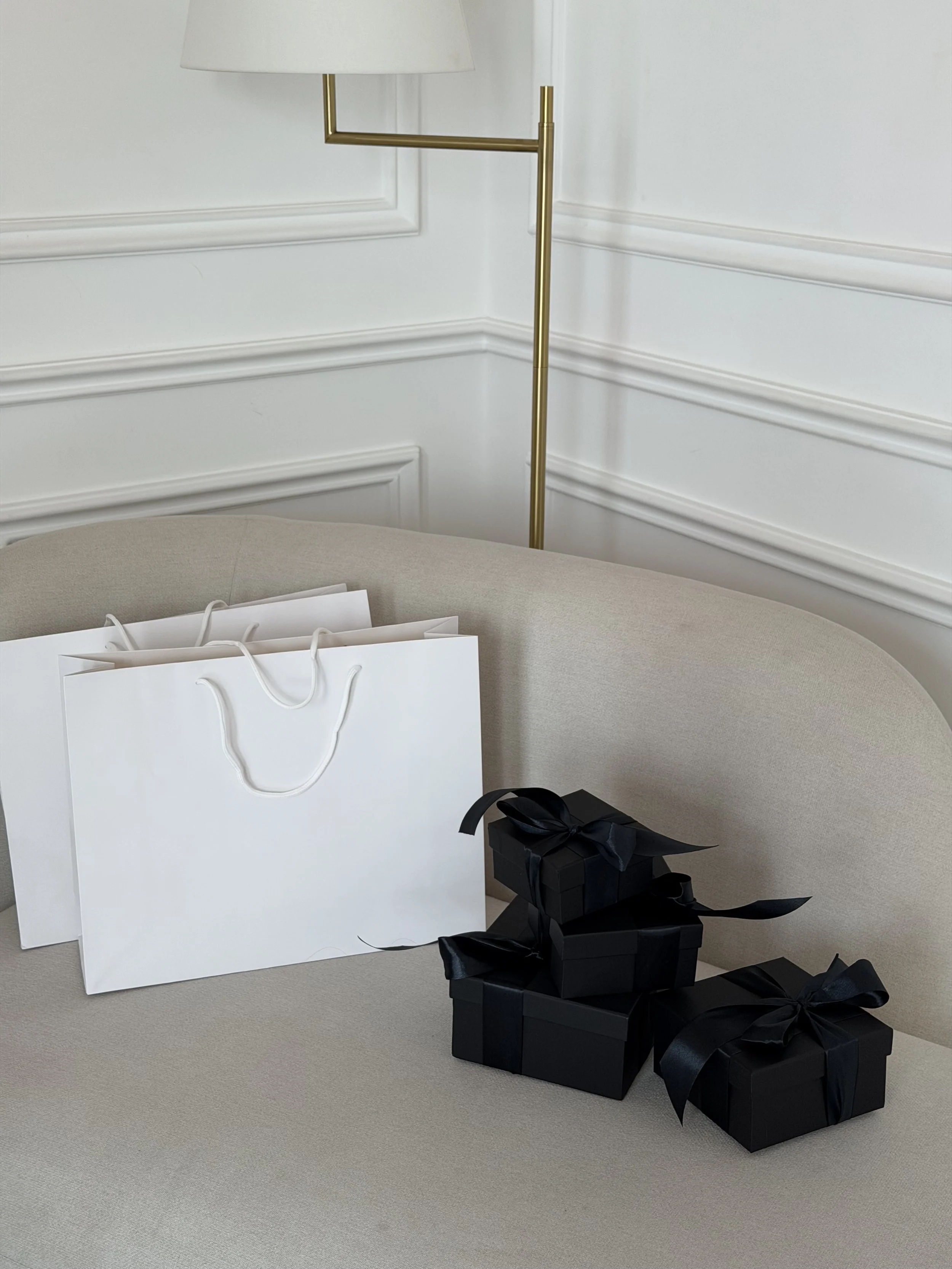 Black Friday website banner image: white shopping bag and black gift boxes on a cream sofa
