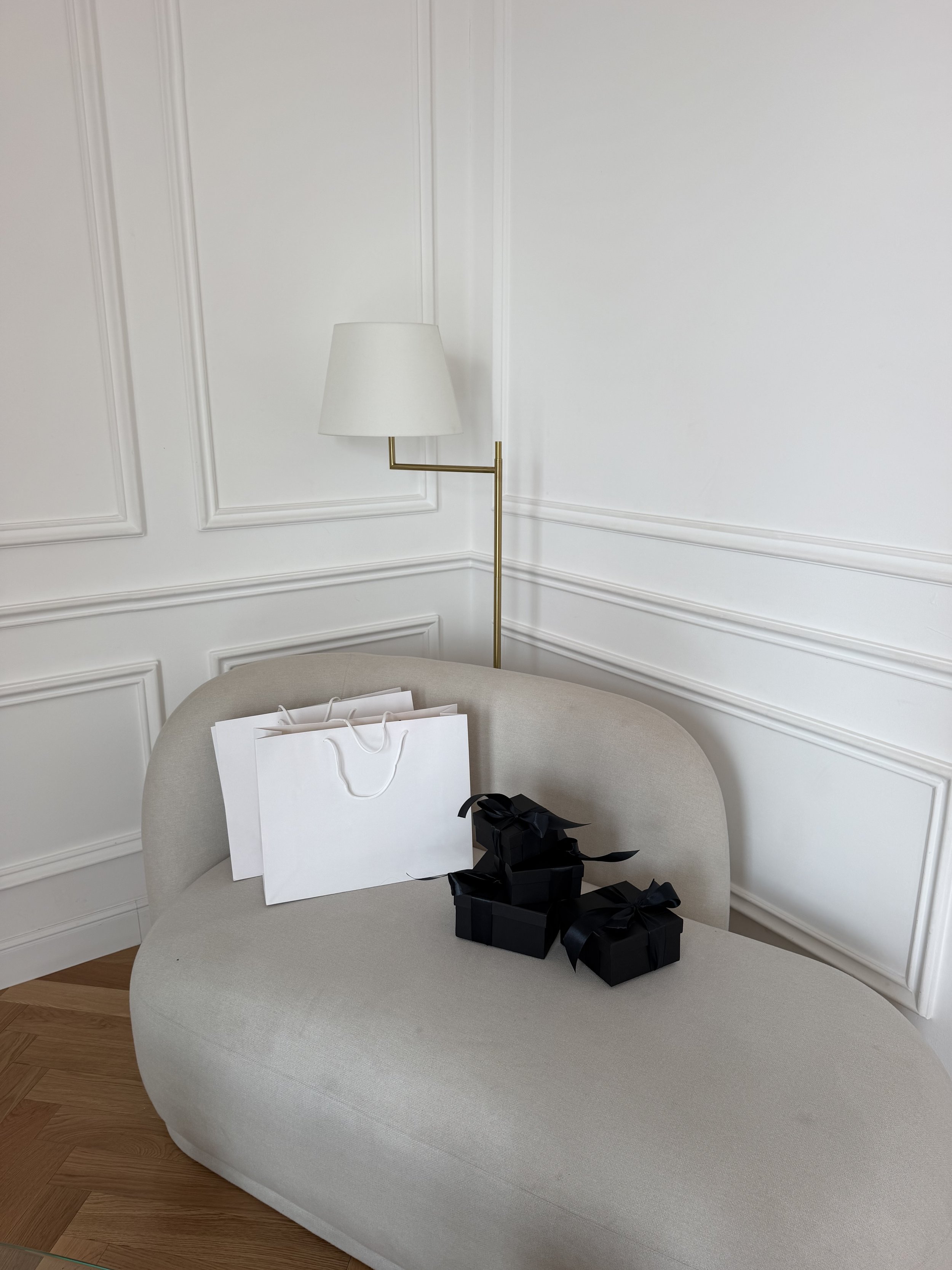 Shopping bag and black gift boxes by a cream sofa and wall lamp, Black Friday email image