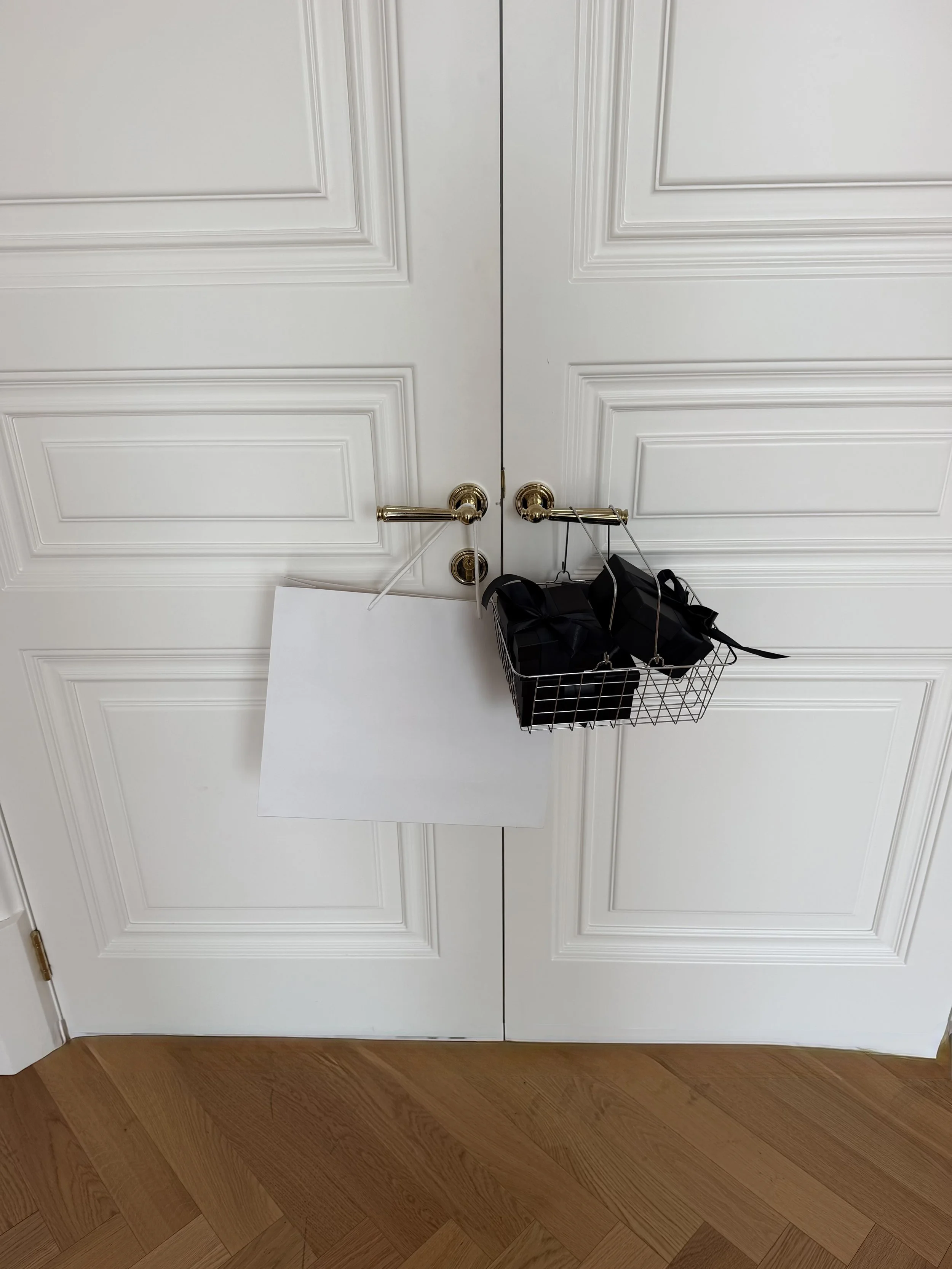 White shopping bag and black gifts hanging on a white double door handle
