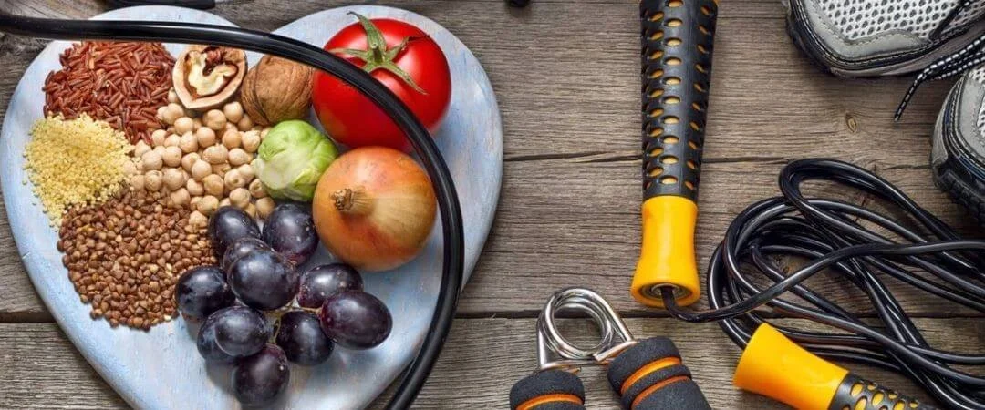 Whole food ingredients and fitness equipment arranged together on a wooden surface.
