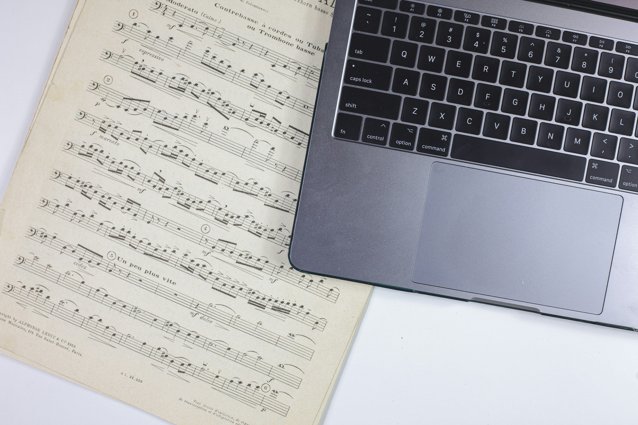 Sheet music with a laptop, indicating the juxtaposition of music's creativity aligned with technical processes.