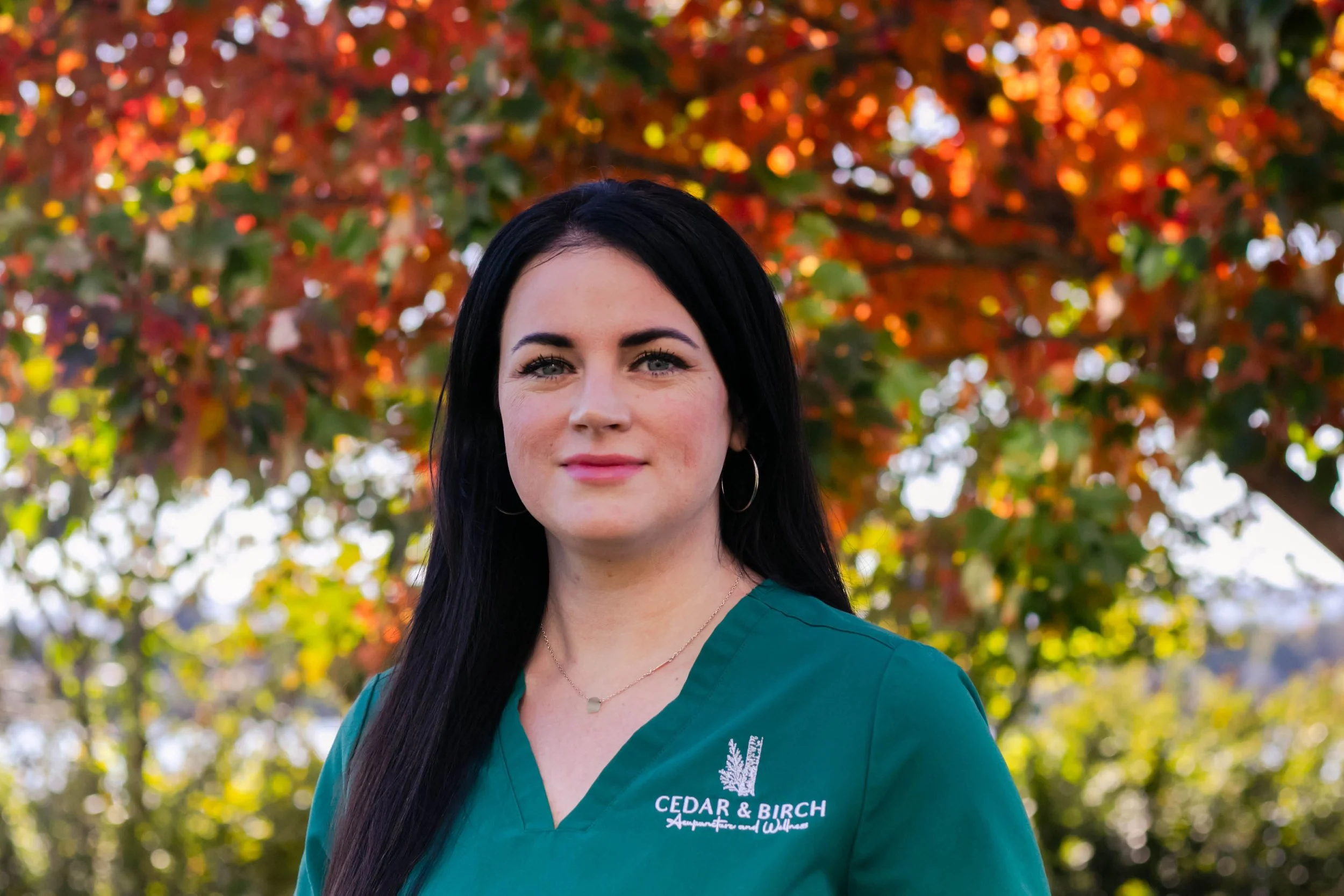 A practitioner with long dark hair wearing a green shirt with the logo and name 'Cedar & Birch'. Kirkland, Washington. Vancouver, Washington. Mental health. Women's health. Fertility. Menopause. Microneedling. Cosmetic acupuncture.