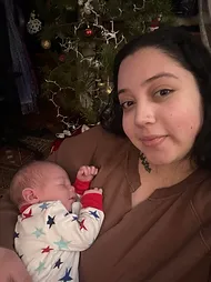 Woman holding sleeping baby in front of Christmas tree