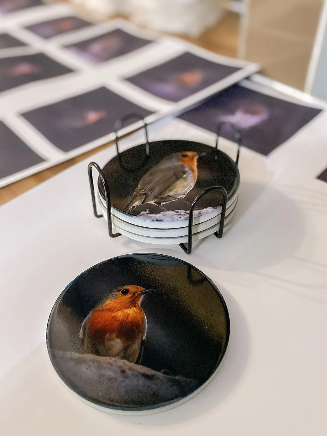 Stack of ceramic coasters with images of a Robin and some paper with images of the robin on ready to be transferred onto the coasters.