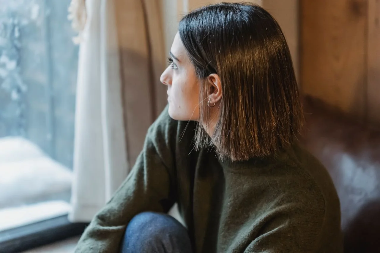 thoughtful-woman-sitting-on-windowsill-in-solitude