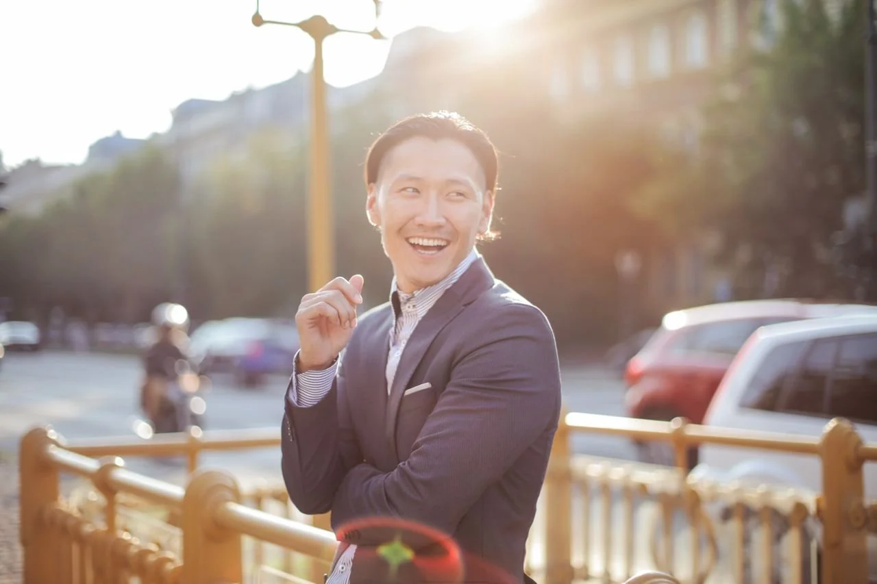 man-in-black-suit-leaning-on-railings-smiling