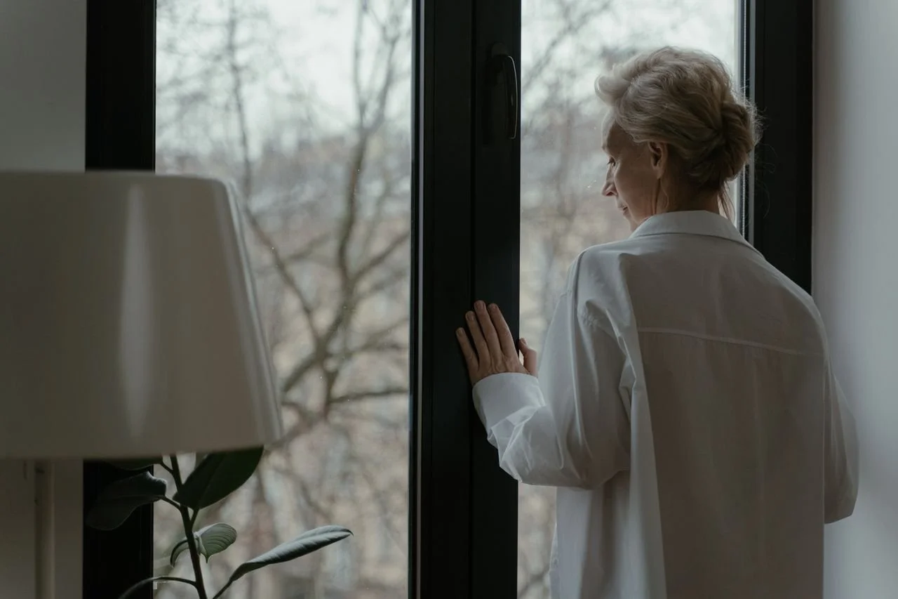an-elderly-woman-looking-through-the-window
