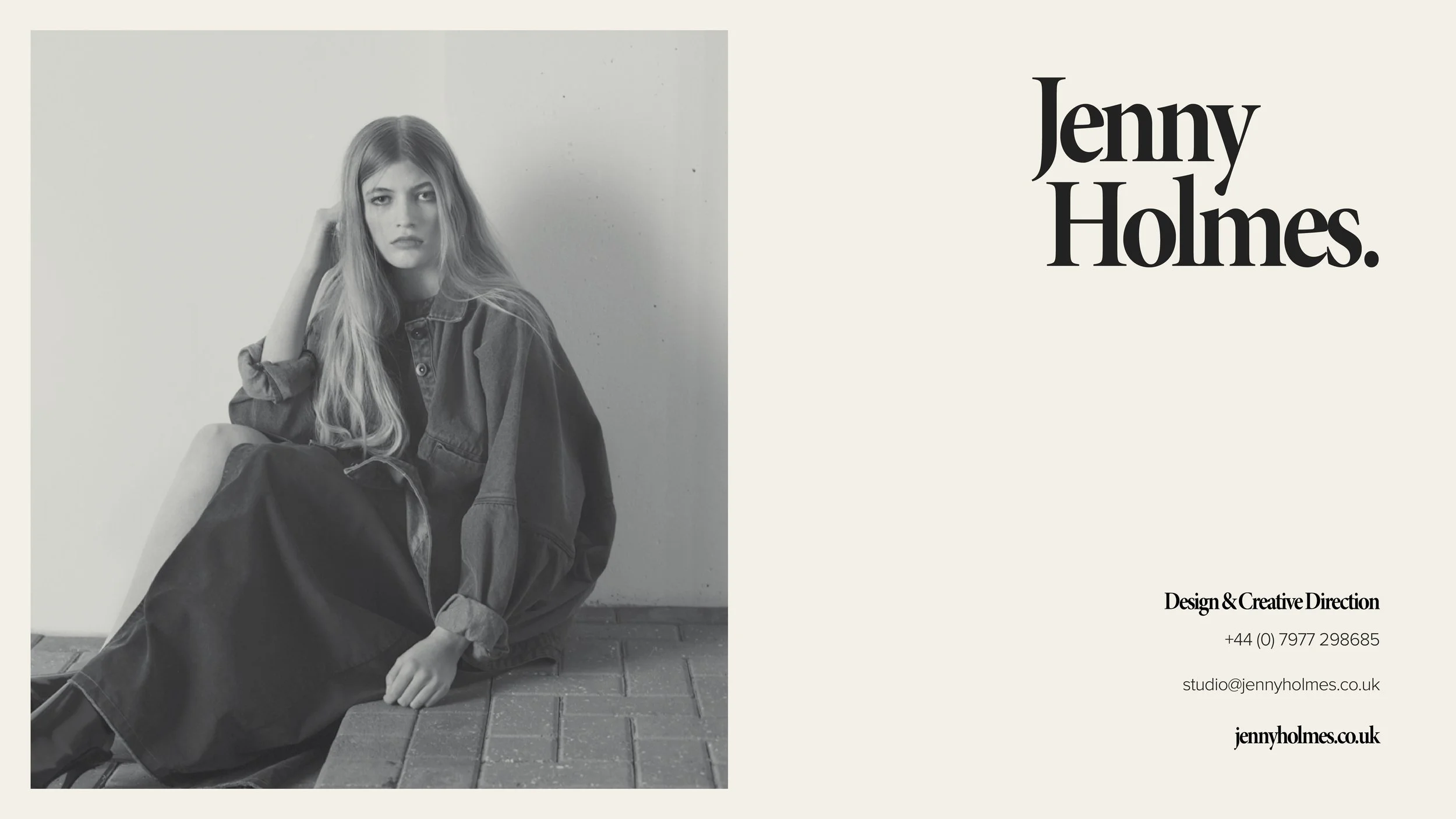 Black and white photo of a young woman with long hair, sitting on a brick-paved ground, wearing a oversized denim jacket and dark skirt, looking at the camera with a serious expression, against a plain wall. To the right, text reads "Jenny Holmes" in
