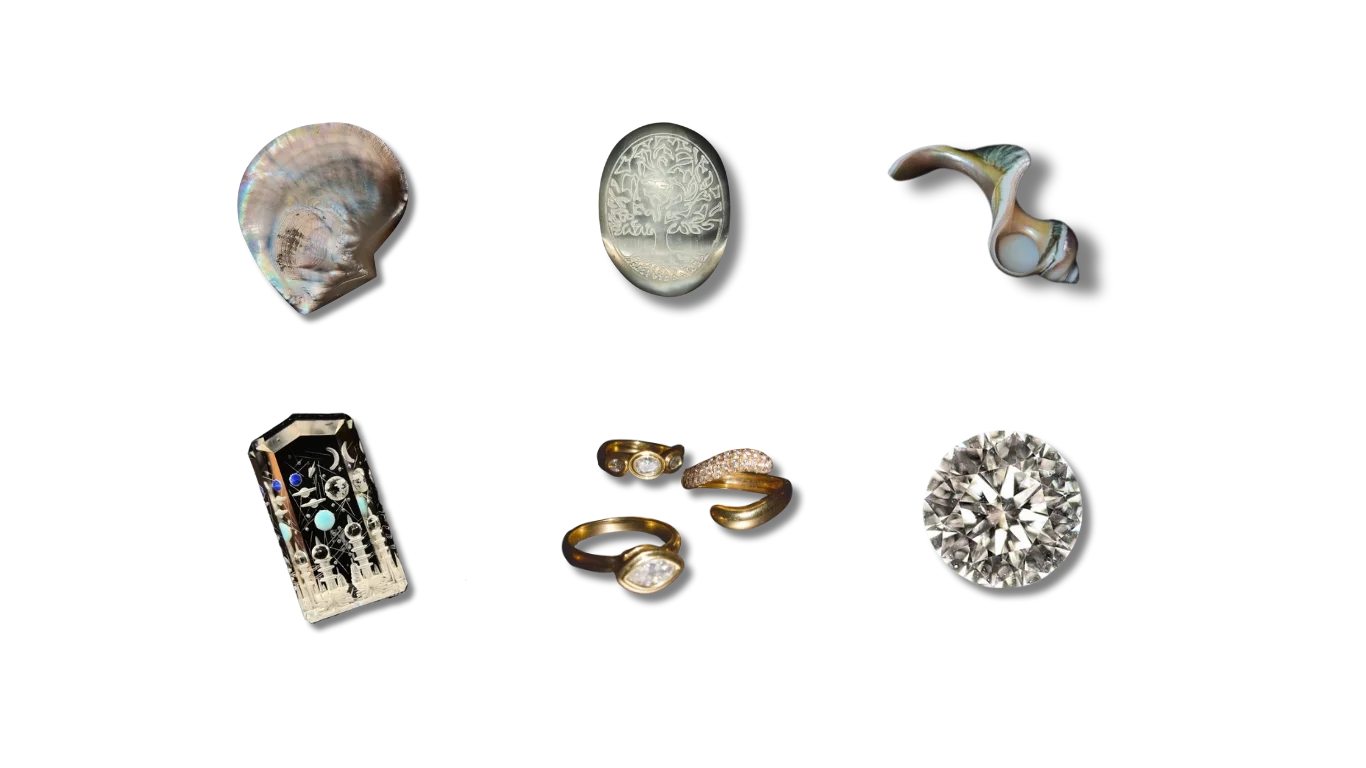 Collection of jewelry and decorative objects on a black background, including shells, an engraved stone, a carved coral, a glass sculpture, a set of gold rings with diamonds, and a cut diamond