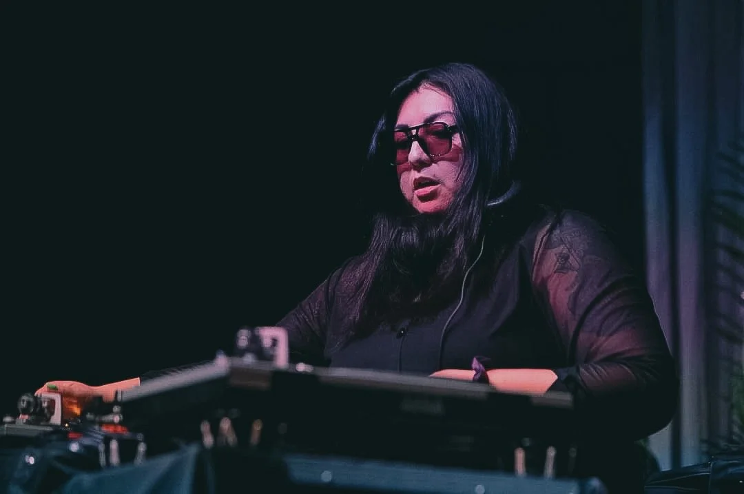 DJ Raquiqui performing a vinyl DJ set at an event in Austin, Texas blending Latin, disco, soul, and house music.